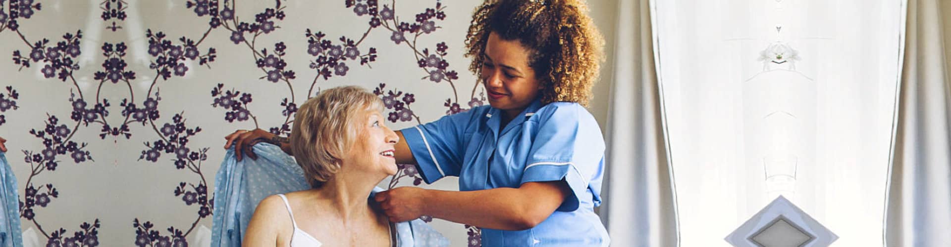 caregiver assiting senior woman to dress up